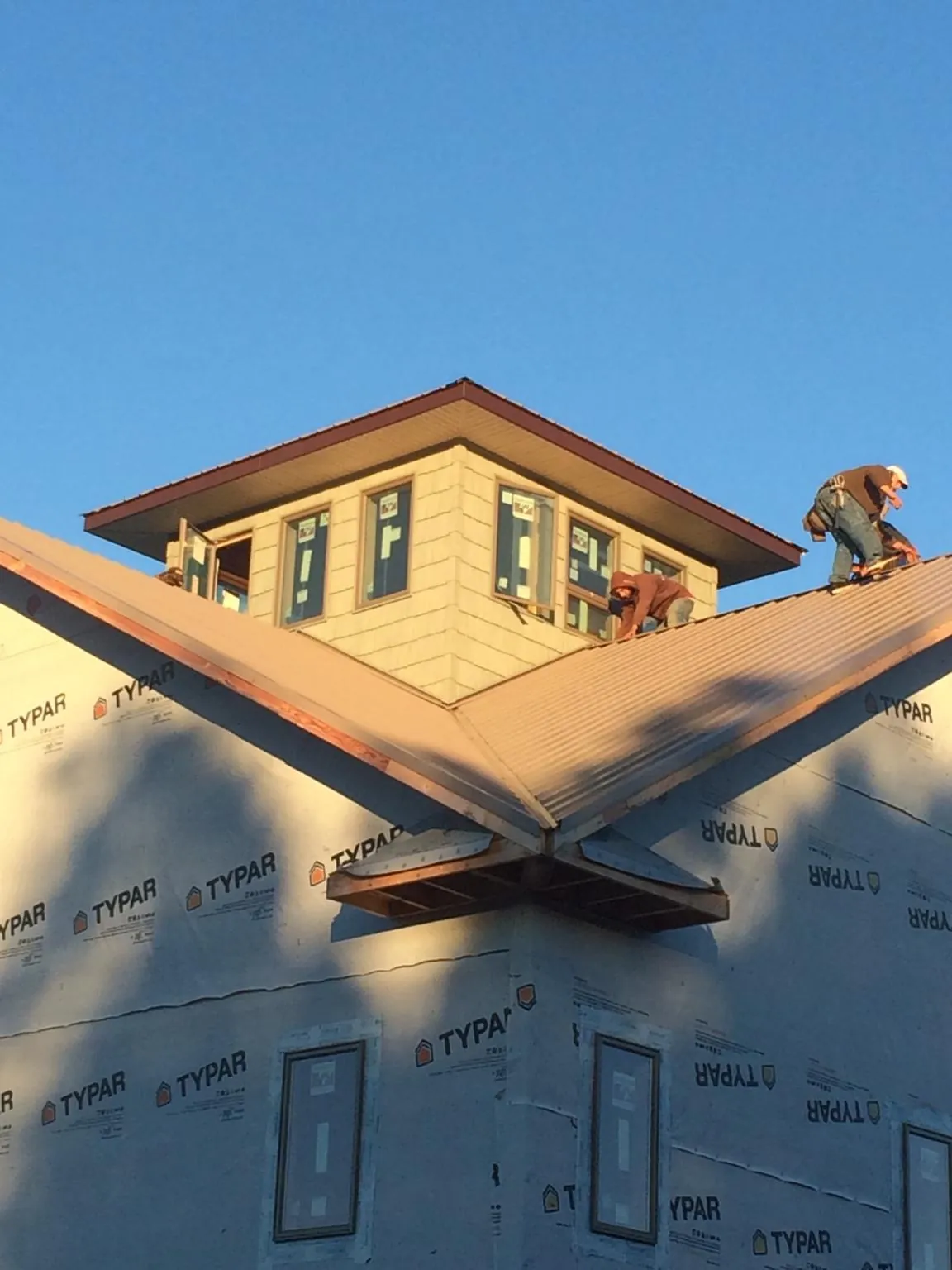 Roofers working around a rooftop cupola on a new metal roof at sunset — Roof Waterproofing in Appleton by Roofing Brothers